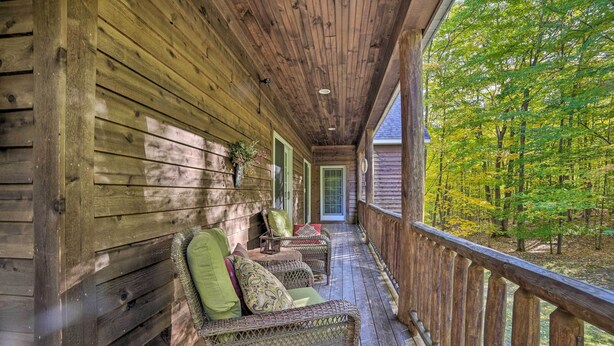 A wooden porch with wicker furniture and a view of a forest.