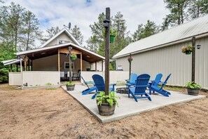 A covered patio area with blue Adirondack chairs and potted plants. - Walk to Castle Rock County Park: Rustic Cabin (Friendship)