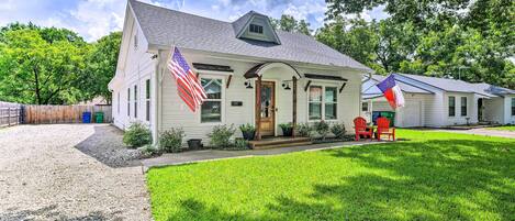 A single-story house with a front porch, a flag, and a small lawn.