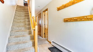 Un escalier avec une rampe en bois, des marches recouvertes de moquette et une étagère en bois fixée au mur.