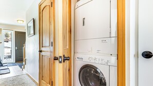 Une buanderie équipée d’un lave-linge et d’un sèche-linge à chargement frontal, de portes en bois et d’une poignée de porte bien visible.