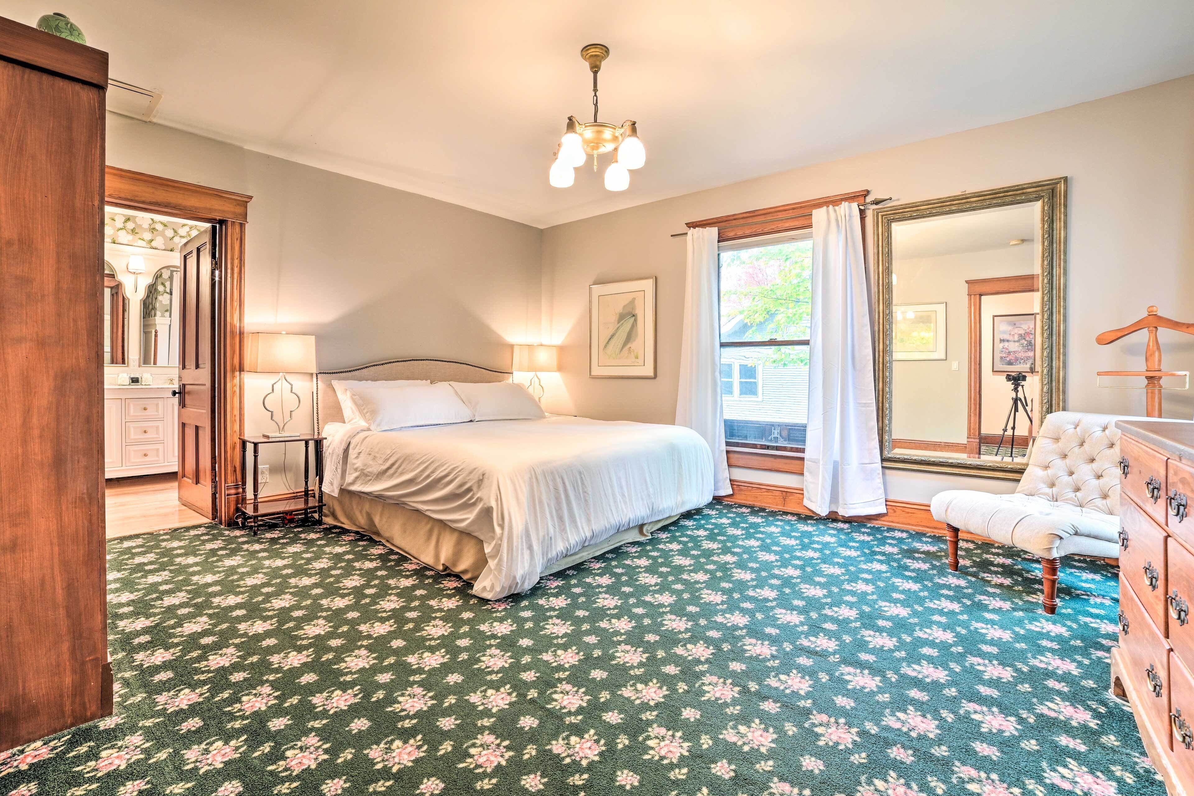 A bedroom with a bed, a dresser, a mirror, and a window with curtains.