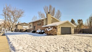 A residential house with a garage, a driveway covered with snow, and a clear sky.