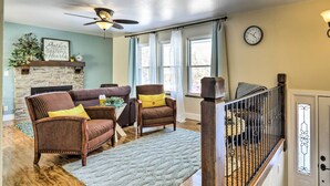 A living room with a fireplace, wicker chairs, a sofa, and a staircase.