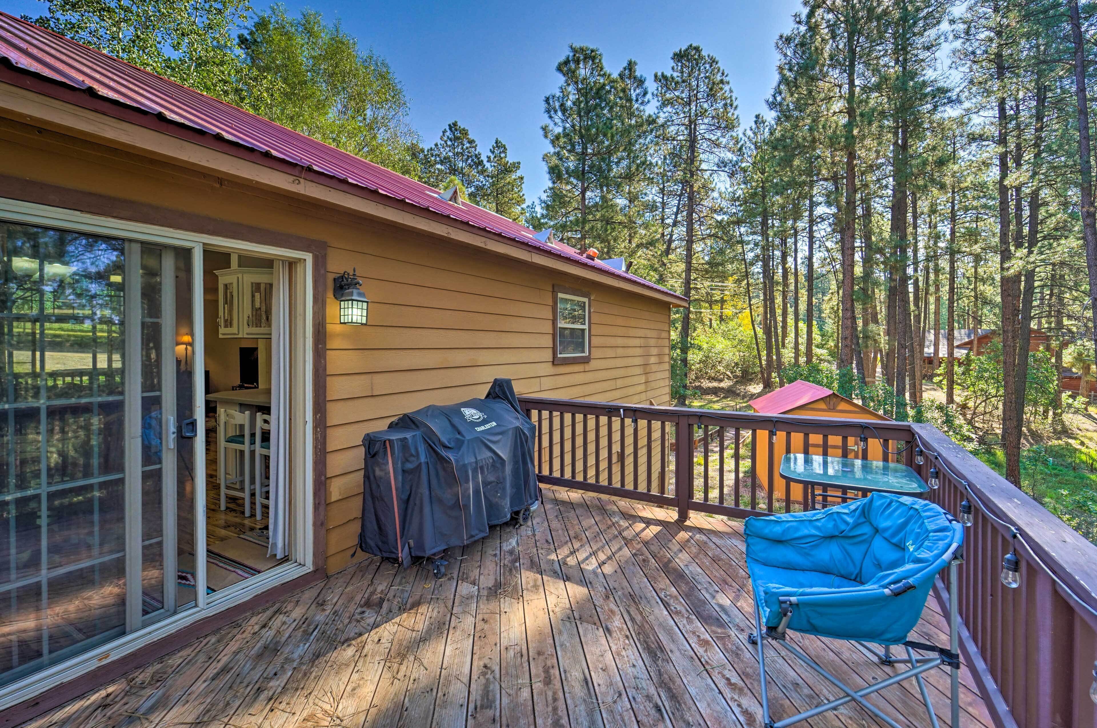 A wooden deck with a covered grill, a blue chair, and a small table.