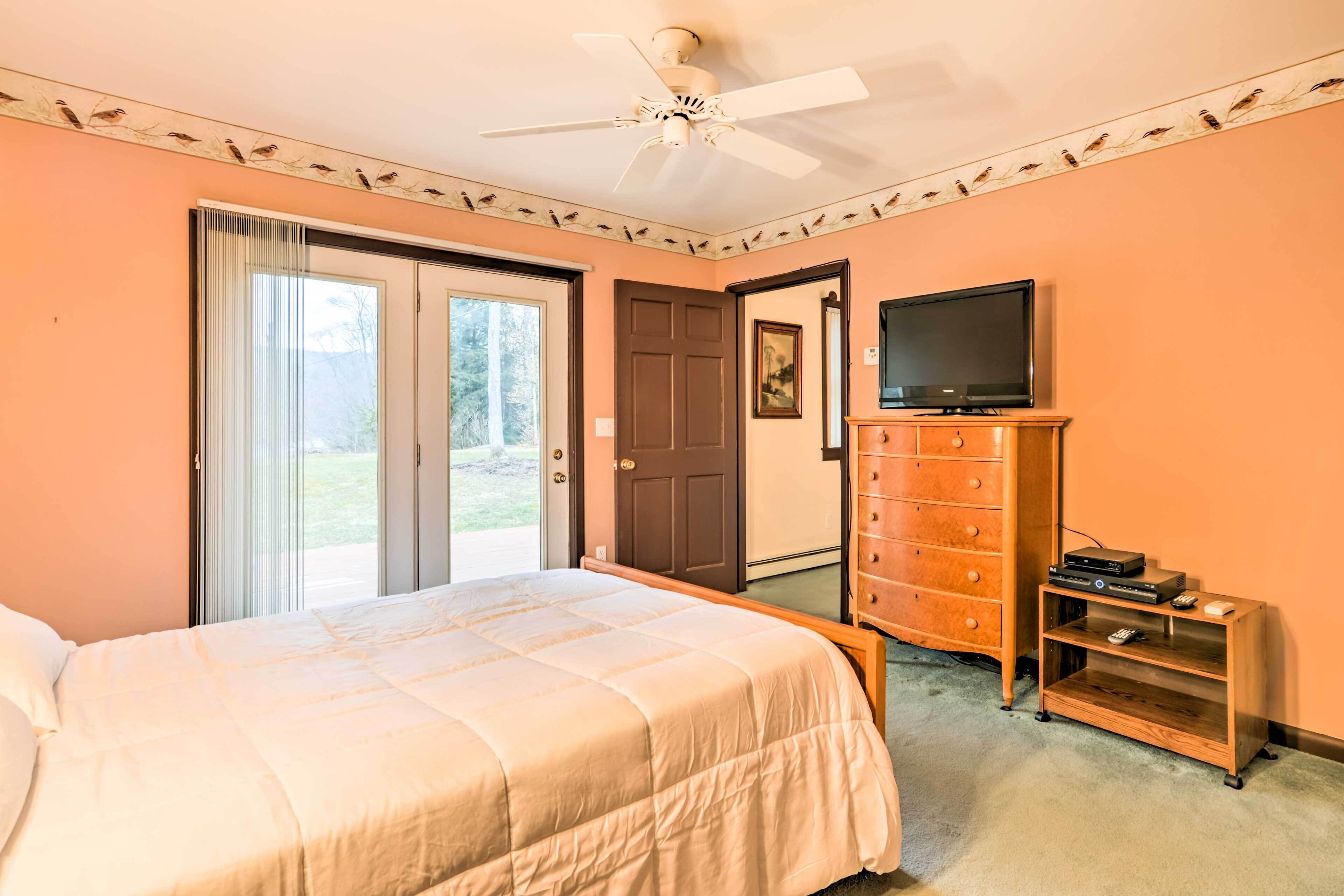 A bedroom with a bed, a dresser, a television, and a ceiling fan.