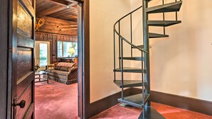 Una escalera conduce a un dormitorio con una puerta de madera, un sofá y una lámpara.