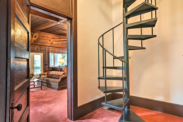 Una escalera que conduce a una habitación con una puerta de madera, un sofá y una lámpara.