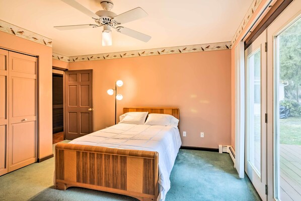 A bedroom with a wooden bed, a ceiling fan, and a large window.