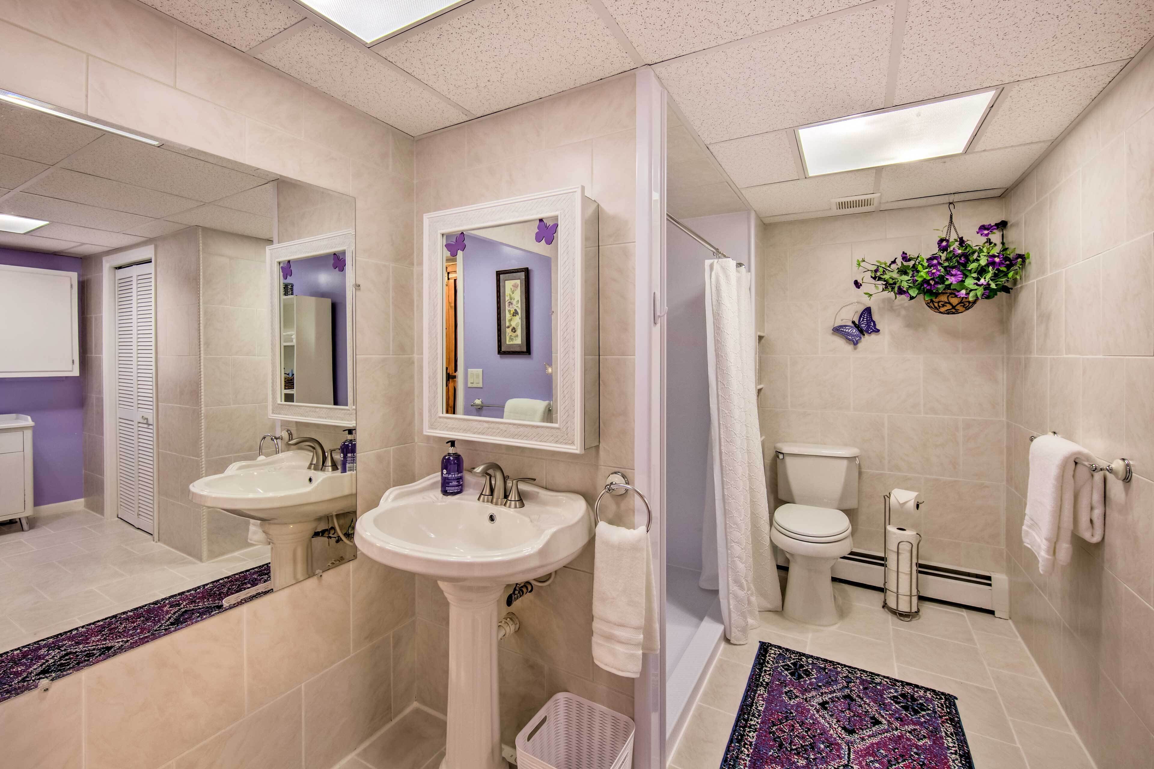 A bathroom with two sinks, a toilet, a shower, and a mirror.