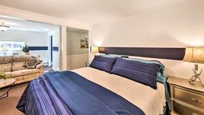 A hotel room with a large bed, a nightstand, a lamp, a sofa, and a view of the hallway. - Lovely Moshannon Ground Apartment w/ Fire Pit (Moshannon)