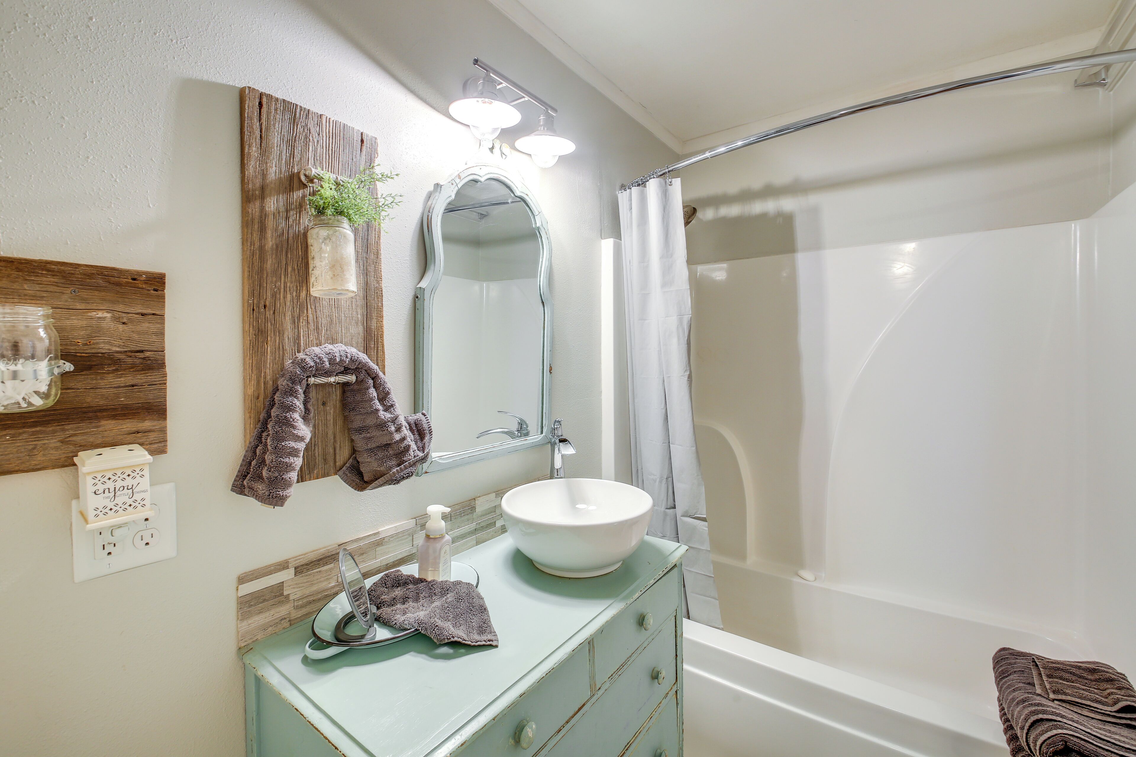 A bathroom with a white sink, a mirror, a towel rack, and a shower curtain.