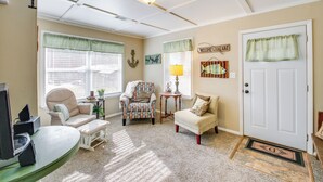 A cozy living room with a beige carpet, a white door, and a green window valance. - Home w/ Ouachita River & Lake Hamilton Access (Mountain Pine)