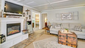 A living room with a fireplace, a television, a sofa, and a decorative trunk. - Home w/ Ouachita River & Lake Hamilton Access (Mountain Pine)