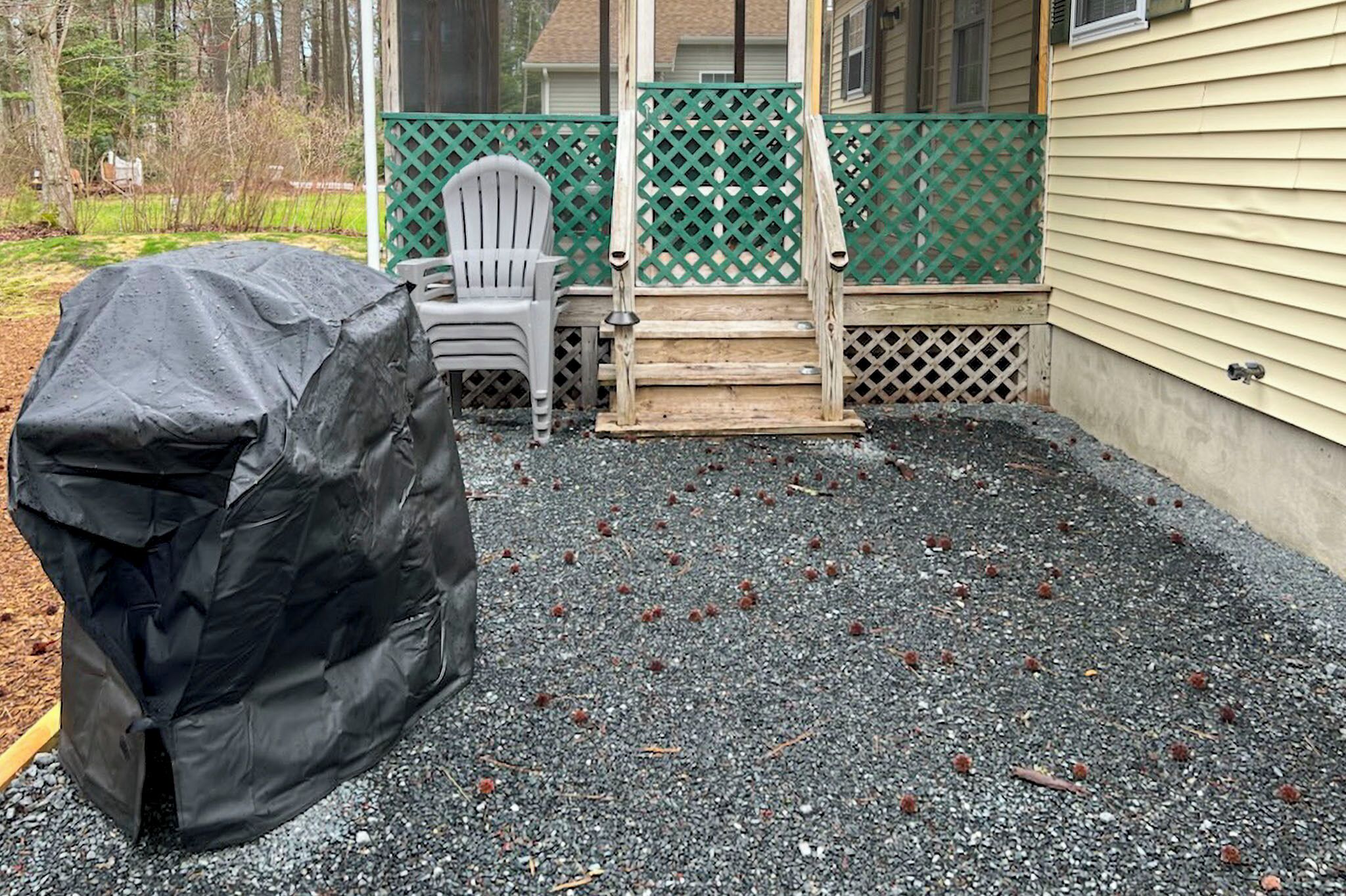 A covered outdoor area with a covered object, a wooden ladder, and a chair.