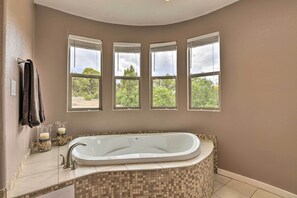A bathroom with a freestanding bathtub, a window with a view of trees, and a towel rack with towels. - Luxe 5-acre Mancos Home ~ 1 Mi to Mesa Verde (Mancos)