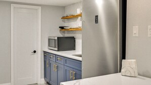 A modern kitchen with a stainless steel refrigerator, a microwave, and blue cabinets.