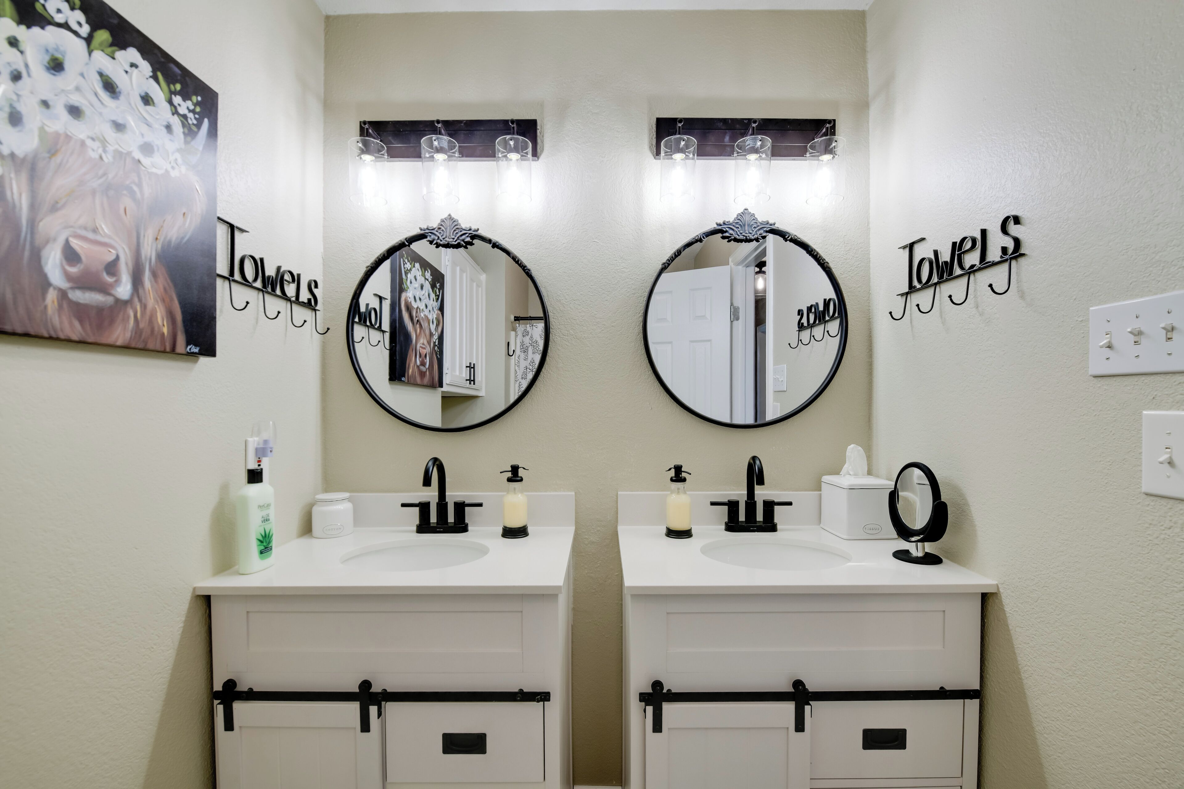 Un baño con dos lavamanos, espejos y un perchero para toallas.