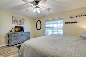 Um quarto com uma cama, cômoda, ventilador de teto e obras de arte nas paredes.