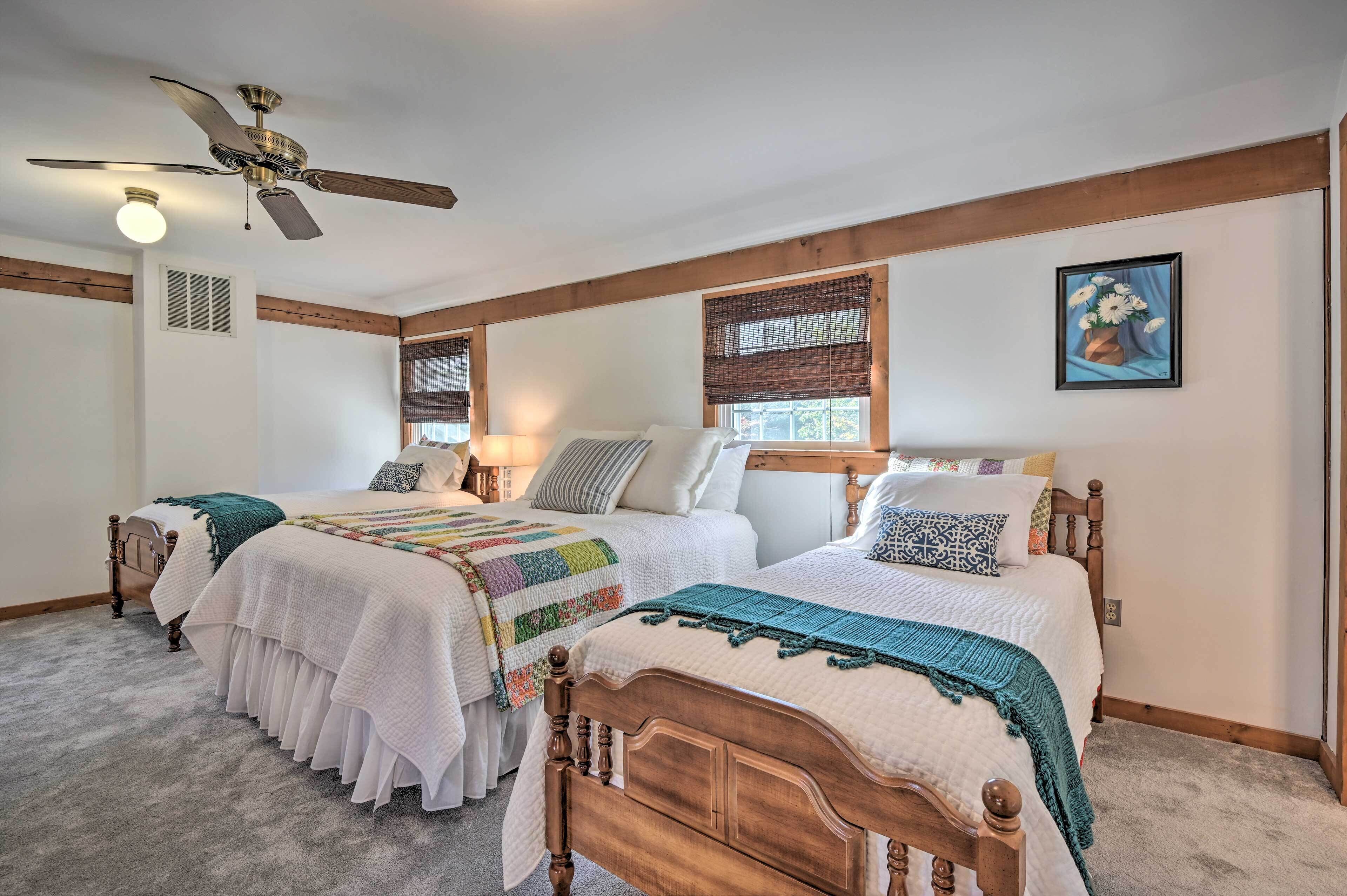 A bedroom with two beds, a ceiling fan, and a painting on the wall.