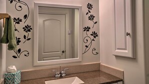 Ein Badezimmer mit weißer Tür, einem Spiegel, einem Waschbecken und dekorativen Wandstickern.