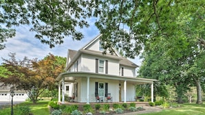 A two-story house with a covered porch, a front yard with a lawn, and a small garden area. - Lush, Modern Farmhouse w/ Mtn Views & Sunroom (Edinburg)