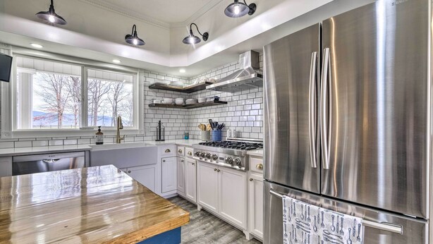 A modern kitchen with white cabinets, stainless steel appliances, and a wooden island. - Lush, Modern Farmhouse w/ Mtn Views & Sunroom (Edinburg)