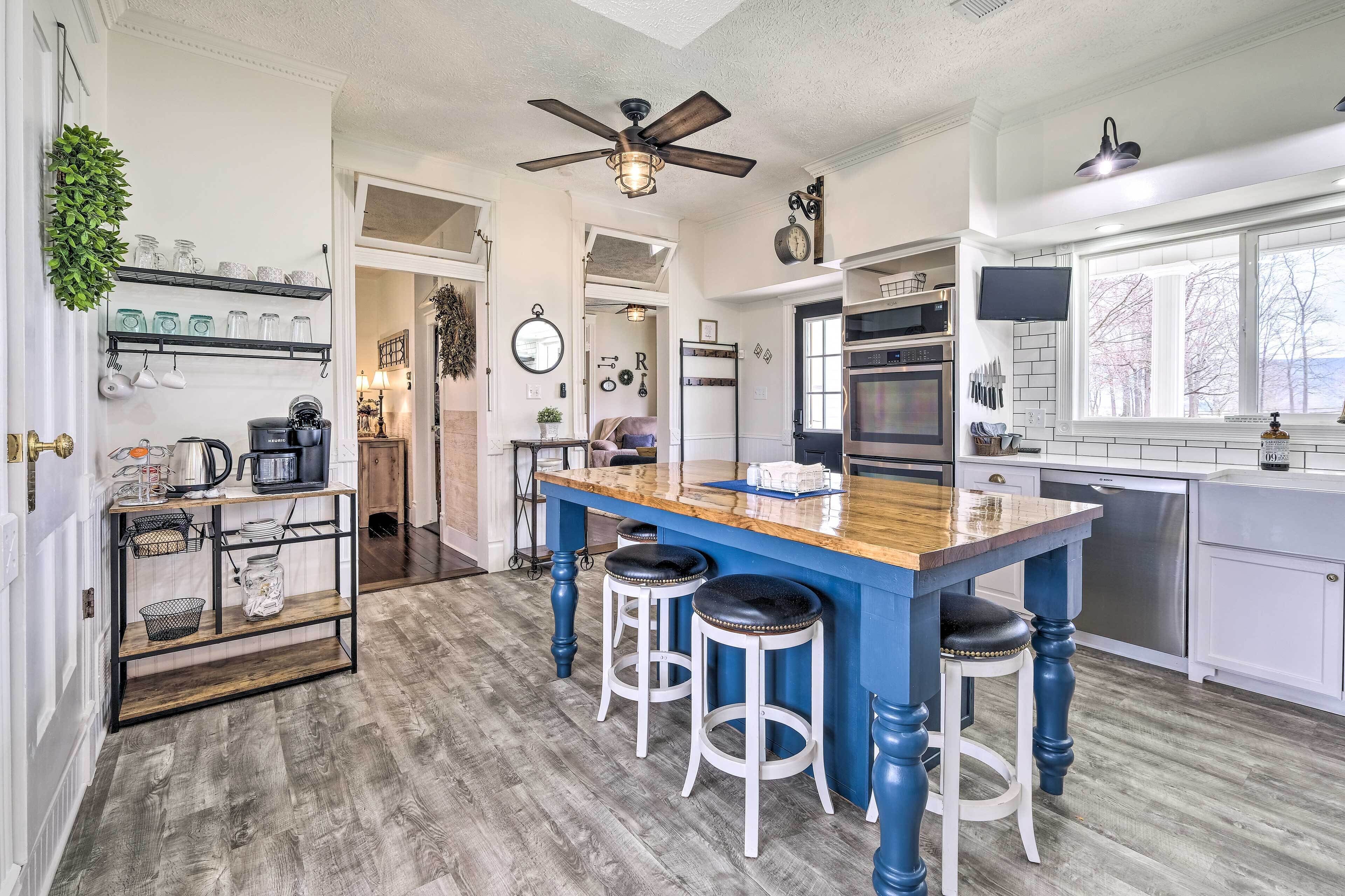 A kitchen with a blue island, white cabinets, and a ceiling fan.