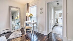 A room with a white table, a chair, a mirror, and a rug. There is a window with blinds and a lamp on the table. - Lush, Modern Farmhouse w/ Mtn Views & Sunroom (Edinburg)