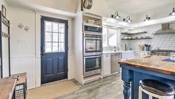 A modern kitchen with a black door, stainless steel appliances, and a blue island.