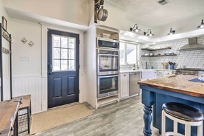Una cocina moderna con puerta negra, electrodomésticos de acero inoxidable y una isla azul.