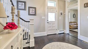 A hallway with a staircase, a white door, and a leather couch in the background. - Lush, Modern Farmhouse w/ Mtn Views & Sunroom (Edinburg)