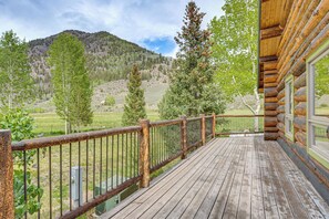 A wooden deck with a metal railing overlooking a mountainous landscape.