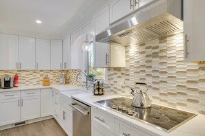 Una cocina moderna con armarios blancos, estufa de acero inoxidable y un original salpicadero hexagonal.