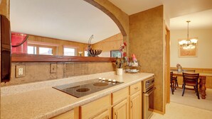 A kitchen with a large island, wooden cabinets, and a dining area with a chandelier. - Mountain-view Angel Fire Escape 'ace's Place' (Angel Fire)