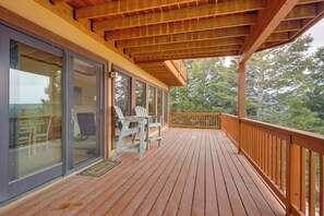 A wooden deck with a railing, a glass door, and a chair.