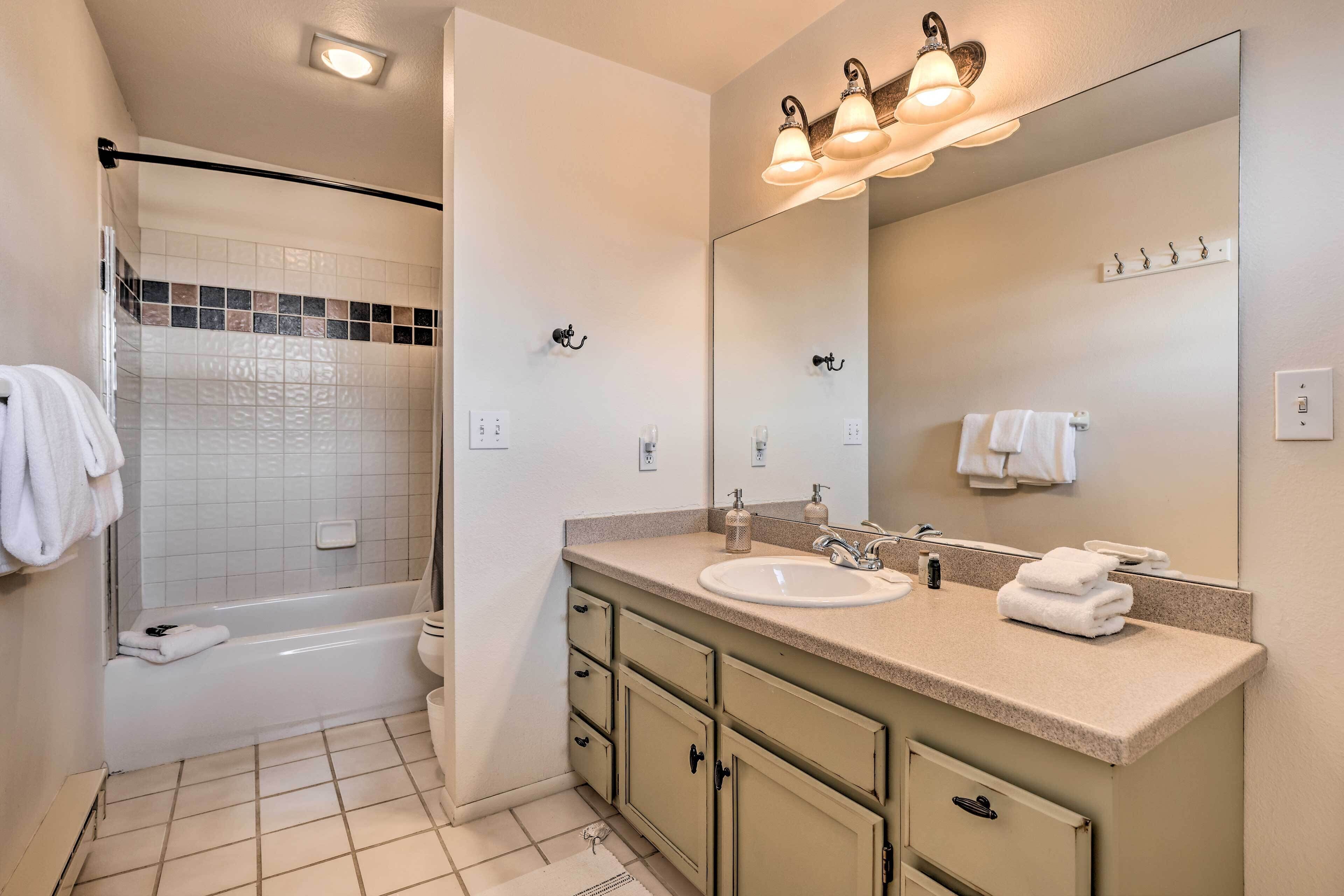 A bathroom with a bathtub, a sink, and a large mirror.