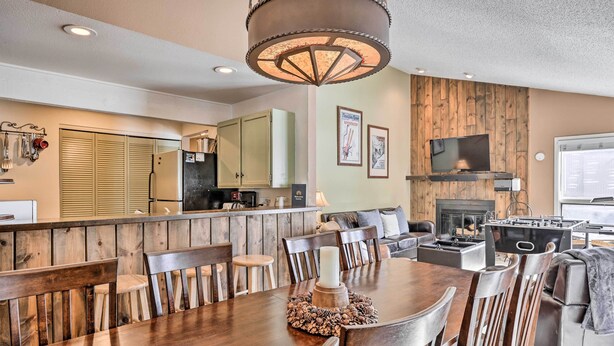 A modern kitchen with wooden cabinets, a built-in stove, and a dining area with a wooden table and chairs. - 3BR Riverfront Retreat 1 Min to Vail or BC Shuttle (Avon)