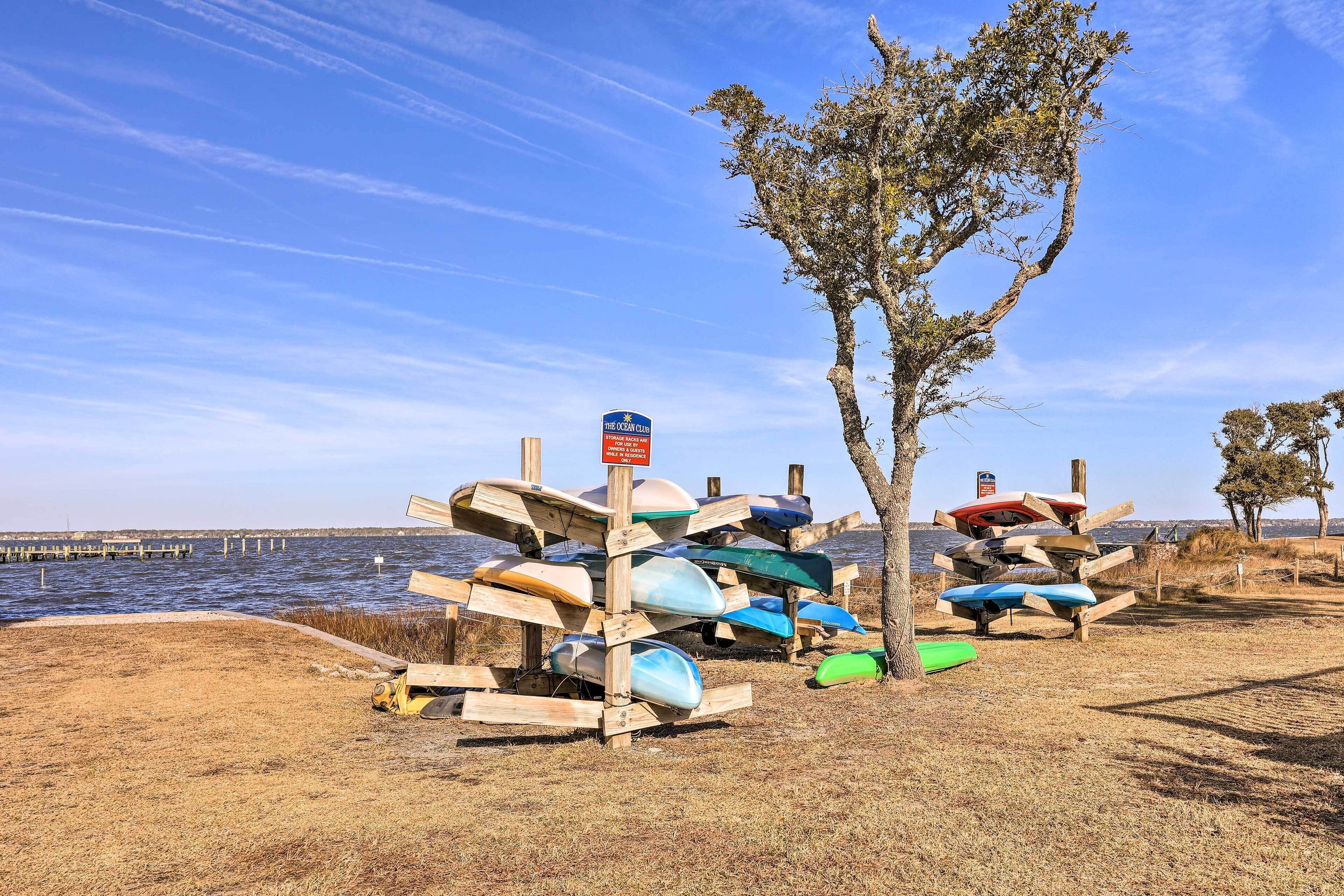 Una estructura de madera con canoas y un letrero que indica un acceso a la playa.