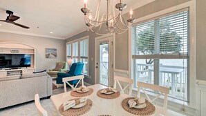 A dining area with a white table, beige placemats, and a chandelier. - Ocean Club Condo w/ Community Pool & Hot Tub (Atlantic Beach)