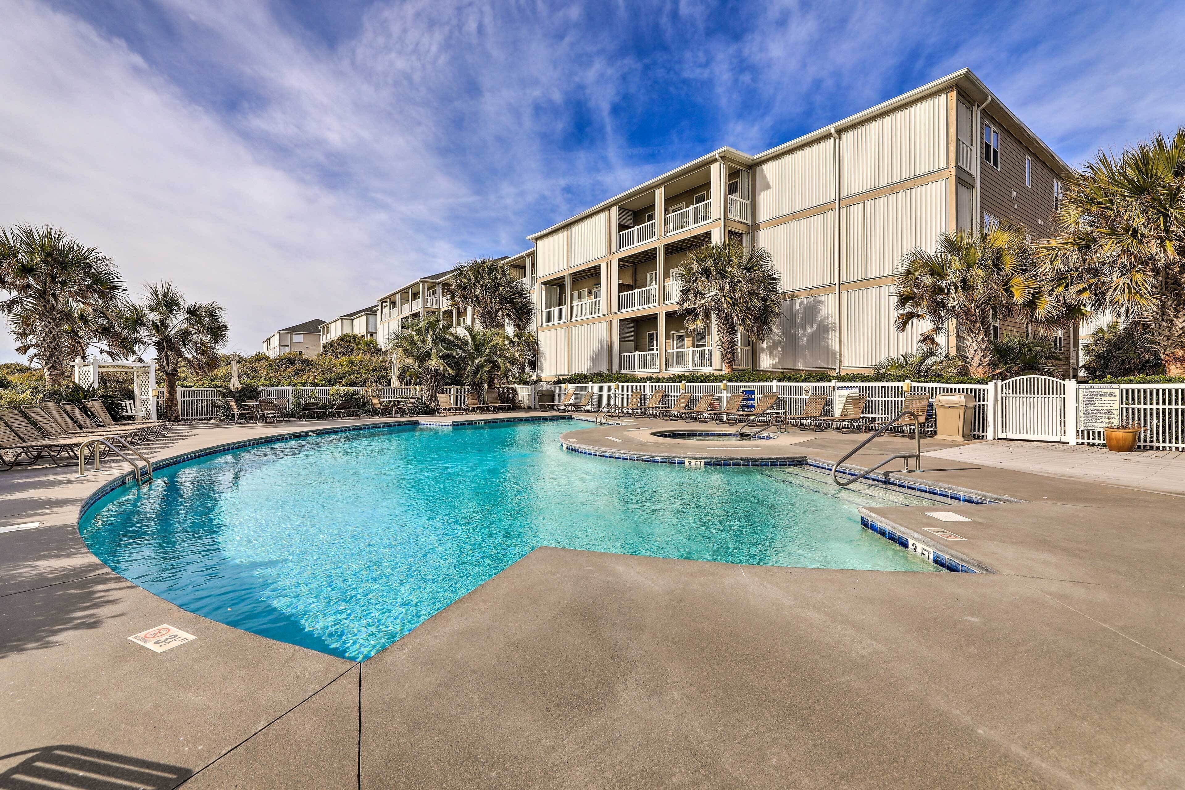 A swimming pool with a curved design, surrounded by lounge chairs and palm trees.
