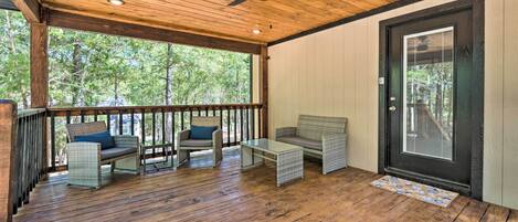 A covered porch with wooden flooring, wicker furniture, and a ceiling fan.