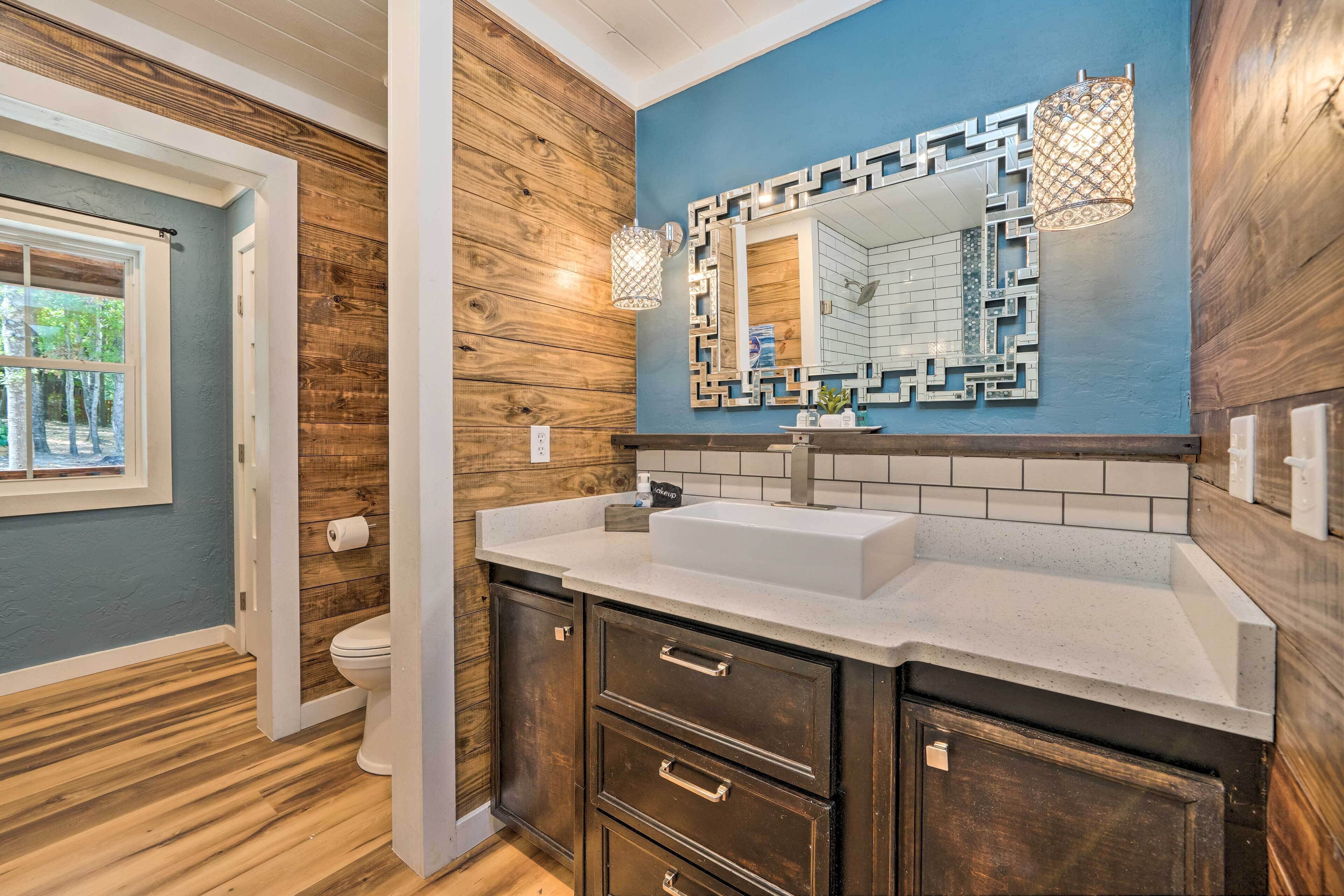A bathroom with wooden paneling, a white sink, and a mirror with a geometric frame.