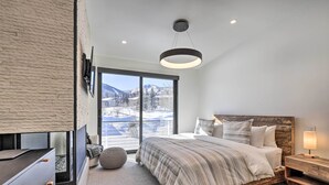 A bedroom with a large window, a bed, a bedside table, and a modern light fixture. - Luxe Park City Townhome w/ Hot Tub: 1/2 Mi to Lift (Park City)