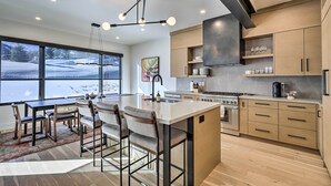 A modern kitchen with a large island, bar stools, and a view of a snowy landscape through large windows. - Luxe Park City Townhome w/ Hot Tub: 1/2 Mi to Lift (Park City)