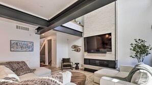 A modern living room with a fireplace, white sofas, a coffee table, and a large flat-screen TV mounted on the wall. - Luxe Park City Townhome w/ Hot Tub: 1/2 Mi to Lift (Park City)