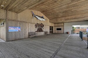 Una amplia terraza de madera con una escultura de pez y un letrero que anuncia una exhibición de tortugas.