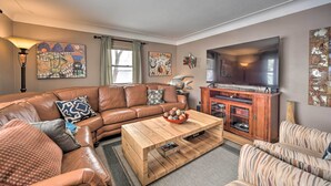 A living room with a brown leather sofa, a wooden coffee table, and a television on a wooden cabinet.