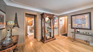 A spacious living room with hardwood flooring, a wooden coffee table, a glass display cabinet, and a framed map on the wall.