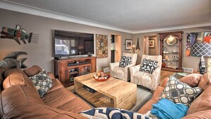 A living room with a brown leather sofa, a wooden coffee table, and striped armchairs.